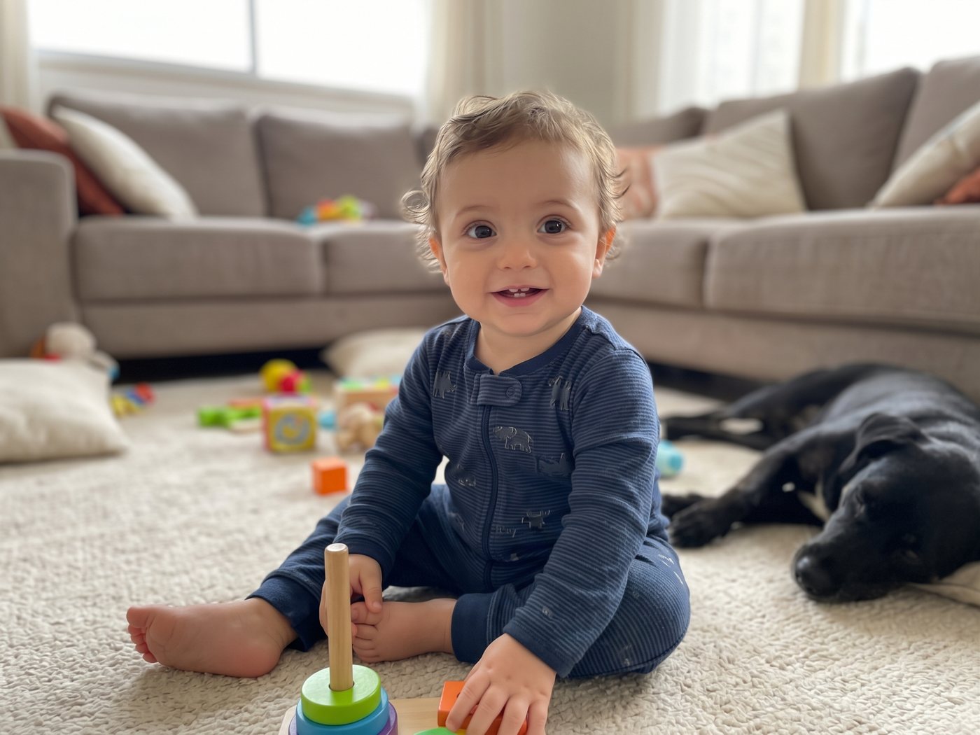 Imagem gerada por IA de um bebê sorrindo, sentado no tapete com brinquedos e um cachorro preto ao lado